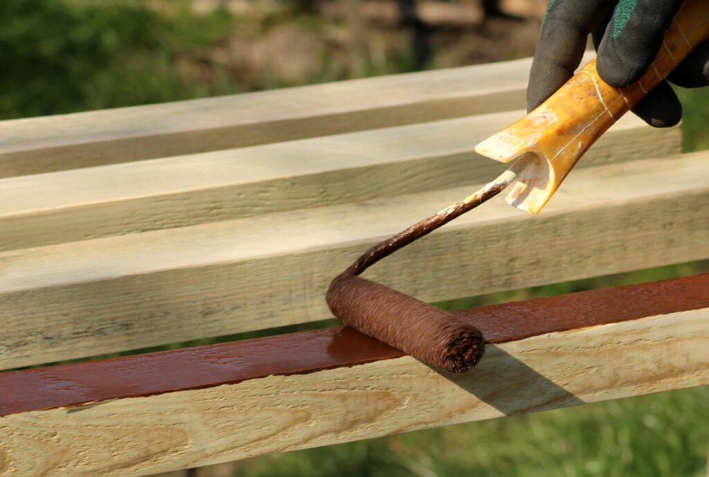 Protective finish being applied to wood, showing why outdoor kitchen materials must handle weather exposure.