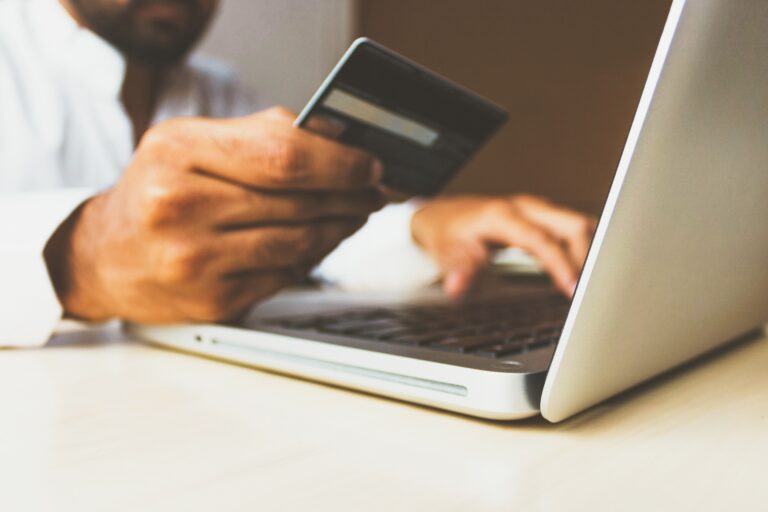 Shopper holding a payment card while using a laptop for online checkout.